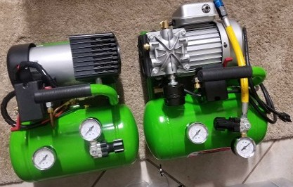 two compact, green air compressors with attached motors and gauges